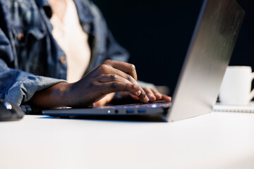 Poster - Close-up of hands of African American individual using laptop keyboard to type, browse the internet, work from home, and engage in freelance work. Black person working on personal computer.