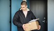© tingting - Modern urban life with delivery, man in black jacket holding cardboard box.