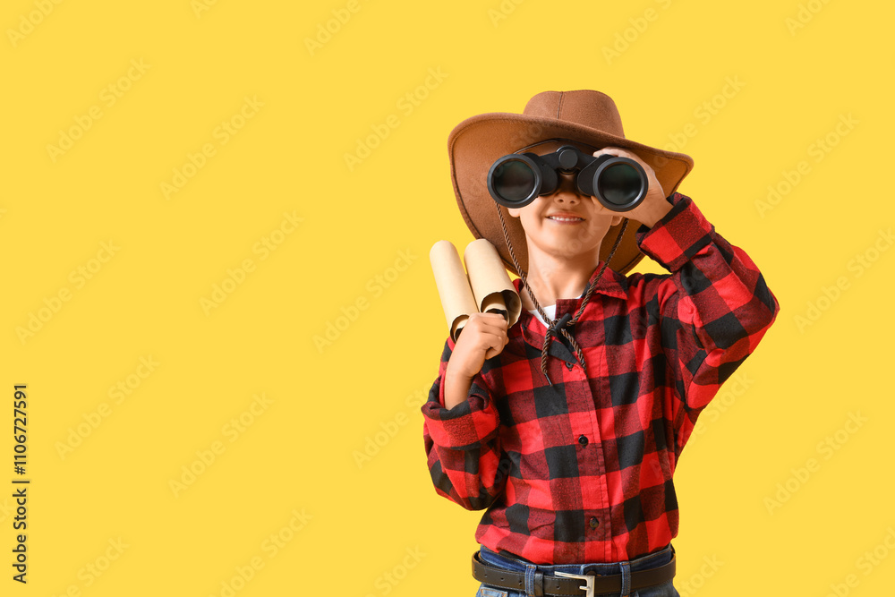 Cute little cowboy with treasure map looking through binoculars on yellow background