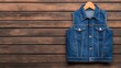 © ChanaphaStudio - A stylish denim vest hung on a wooden background, showcasing casual fashion and timeless design.