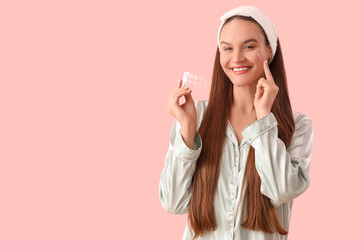 young woman in pajamas with pimple patches on pink background