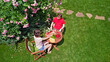 © Iuliia Sokolovska - Young couple enjoying food and drinks in beautiful roses garden on romantic date, aerial drone view from above of man and woman eating and drinking together outdoors in park