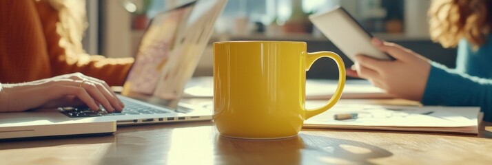 Aufkleber - A yellow mug sits on a table surrounded by laptops and tablets, indicating a work or study session.