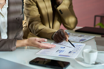 Aufkleber - Hand of mature African American businessman pointing at graphic data on paper document during discussion with colleague