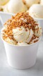 © Kenn W. - Creamy Ice Cream Scoop Topped with Crunchy Crispy Layer and Nuts in a White Cup