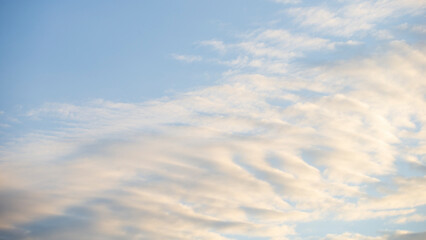 Wall Mural - Clouds in the blue sky at sunset as an abstract background.