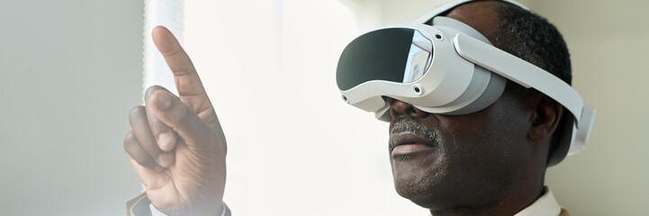 Poster - Banner of aged African American businessman with virtual reality headset pointing at augmented visual board while making presentation