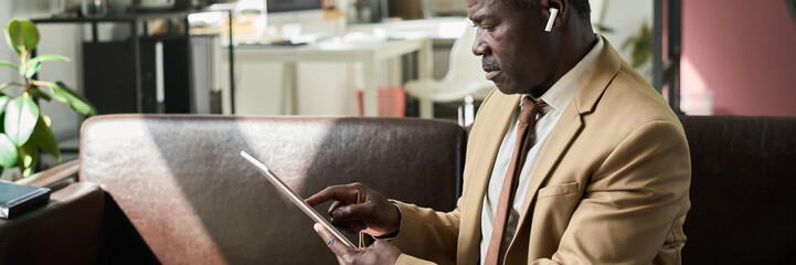 Poster - Banner of mature African American male director of company sitting in front of camera in office and looking through document