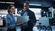 © Gorodenkoff - Portrait of a Team of Two Engineers Collaborating on Developing a Robot for Deliveries in a Manufacturing Facility. Colleagues Analysing Data Using Laptop Computer and Brainstorming for a Project