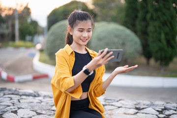 Wall Mural - Smiling young Asian woman using smartphone in urban city checking apps mobile outdoors