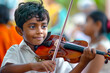 © Indian People Images - A young Indian boy embraces the opportunity to learn a musical instrument, his dedication and practice paying off as he performs in a school concert.