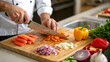 © Chandra - Hands of a chef chopping fresh vegetables on a wooden cutting board with a sharp knife