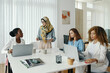 © DragonImages - Group of diverse women engaged in business discussion around meeting table in modern office. Each individual focused on task, collaborating effectively in professional environment
