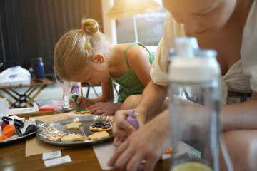 Wall Mural - Mother and her daughter paint Halloween cookies 