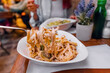 © EdNurg - Creamy tagliatelle pasta with sauce being lifted by a fork in a restaurant, with blurred diners in the background