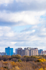 Wall Mural - blue cloudy sky over buildings and colorful park