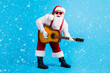 © deagreez - Full body photo of crazy funky pop star santa claus with big beard stomach play guitar instrument on x-mas christmas spirit event wear suspenders overall cap isolated blue color background