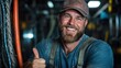 ©  lukaPixMedia - A cheerful worker in a blue shirt giving a thumbs-up sign in an industrial environment, symbolizing approval and positive energy within the workplace.