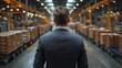 © Thuntaree - Businessman Overlooking Warehouse Operations with Cardboard Boxes