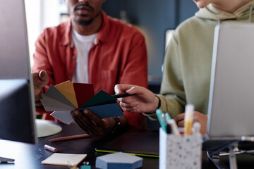 Fototapete - Two individuals engaged in discussion while selecting from color palette samples in modern office setting demonstrating teamwork and consultation