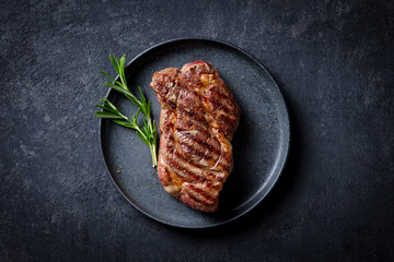 Wall Mural - Beef Steak medium rare on a black plate. Dark background. Close up. Top view.