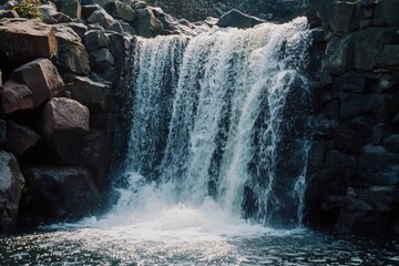 Poster - A large waterfall flows down rocky terrain, surrounded by lush greenery