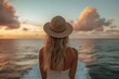 © Peeradontax - A serene image of a woman with long, wavy blonde hair, wearing a wide-brimmed straw hat, gazing at the sunset over the open sea from the deck of a cruise ship.