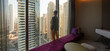 © serikbaib - man in hotel room looking out window at skyscrapers