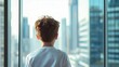 © fotofabrika - Young boy gazes out at a bustling urban skyline from a high-rise building window during daylight hours