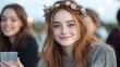 © Lifestyle Images - Close-up portrait of a young girl with long red hair and a flower crown on her head. she is smiling and looking directly at the camera. she has freckles on her face and is wearing a gray sweater.