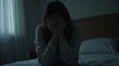 © Alex Pios - A person sitting alone on the edge of a bed in a dimly lit room, head in hands, atmosphere feels heavy and melancholic
