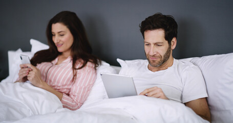 Wall Mural - Phone, tablet and couple relaxing in bed in home for networking, connectivity or browsing online. Happy, rest and young people with cellphone and digital technology in bedroom for contact in house.