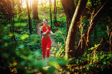 Energetic Woman Running Through a Sunlit Forest Path