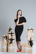 © New Africa - Woman in black dress with Christmas gifts on grey background
