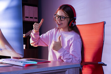 Wall Mural - Happy girl playing video game with keyboard at table indoors