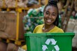 © Vorda Berge - Portrait of a smiling young black female volunteer holding recycle box