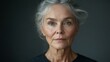 © 楠 刘 - A 70 year old woman wearing a black casual shirt with a gray background presents a realistic style portrait of a modern elderly woman.