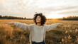 © UniqGraphicX - Young beautiful woman taking fresh air with open arms in a grass field. Smiling woman taking deep breath, healing and relaxation concept