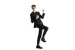 © peshkova - Man in a dynamic celebratory pose wearing asuit and glasses, standing on one leg, isolated on a white background, concept of success
