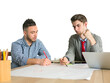© peshkova - Two young men working together on a project at a desk, one writing on paper and the other analyzing. White background, concept of teamwork