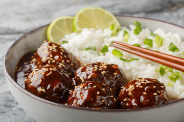 Wall Mural - Asian meatballs coated in the sweet and spicy sauce made with sriracha, soy sauce, ginger, honey and garlic served with rice closeup on the bowl on the table. Horizontal