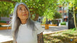 © Krakenimages.com - Woman with grey hair standing outdoors in a park with a thoughtful expression