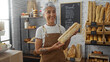 © Krakenimages.com - Mature woman holding a loaf of bread in a bakery shop with various pastries in the background