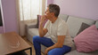 © Krakenimages.com - Young man sitting thoughtfully in a home living room with glasses on a wooden table