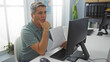 © Krakenimages.com - Young man in office analyzing documents while contemplating at computer