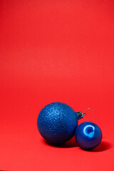 Two blue Christmas ornaments on a vibrant red background, creating a festive contrast.