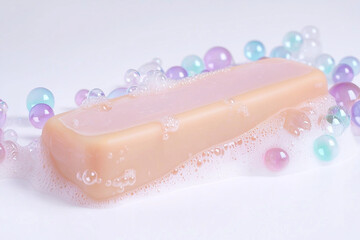 Soap bar surrounded by colorful bubbles and beads on a surface