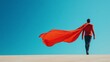 © Blackmint Studio - Heroic figure stands confidently with cape flowing against clear blue sky at sunset