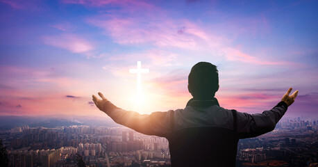 Wall Mural - religious concept. young man praying with cross on sky background.