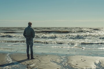 Poster - A person standing alone on a beach with the vast ocean as a backdrop, great for travel and adventure themes